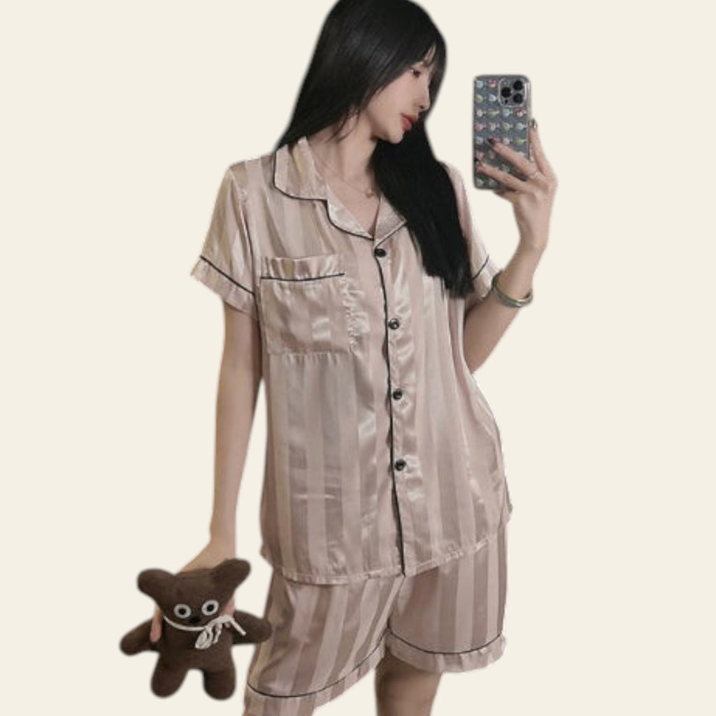 Woman in striped pajama set taking a mirror selfie in a modern room.