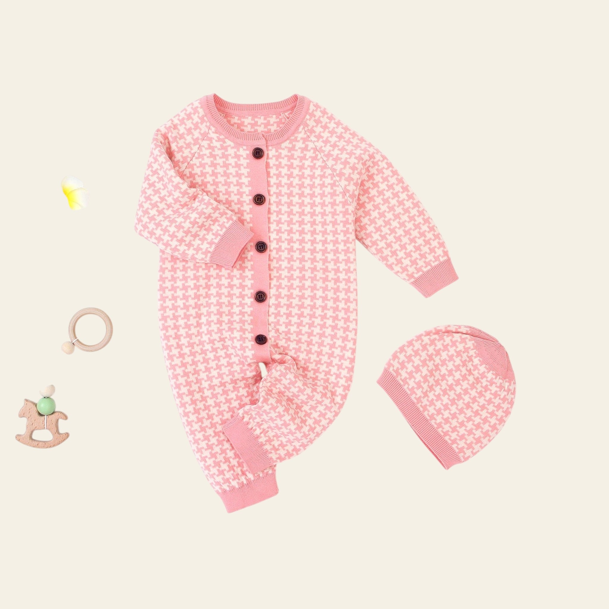 Pink baby outfit with matching hat and toy on a white background