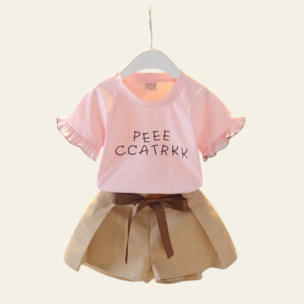 Children's outfit with pink top and beige shorts on a hanger against a gray background