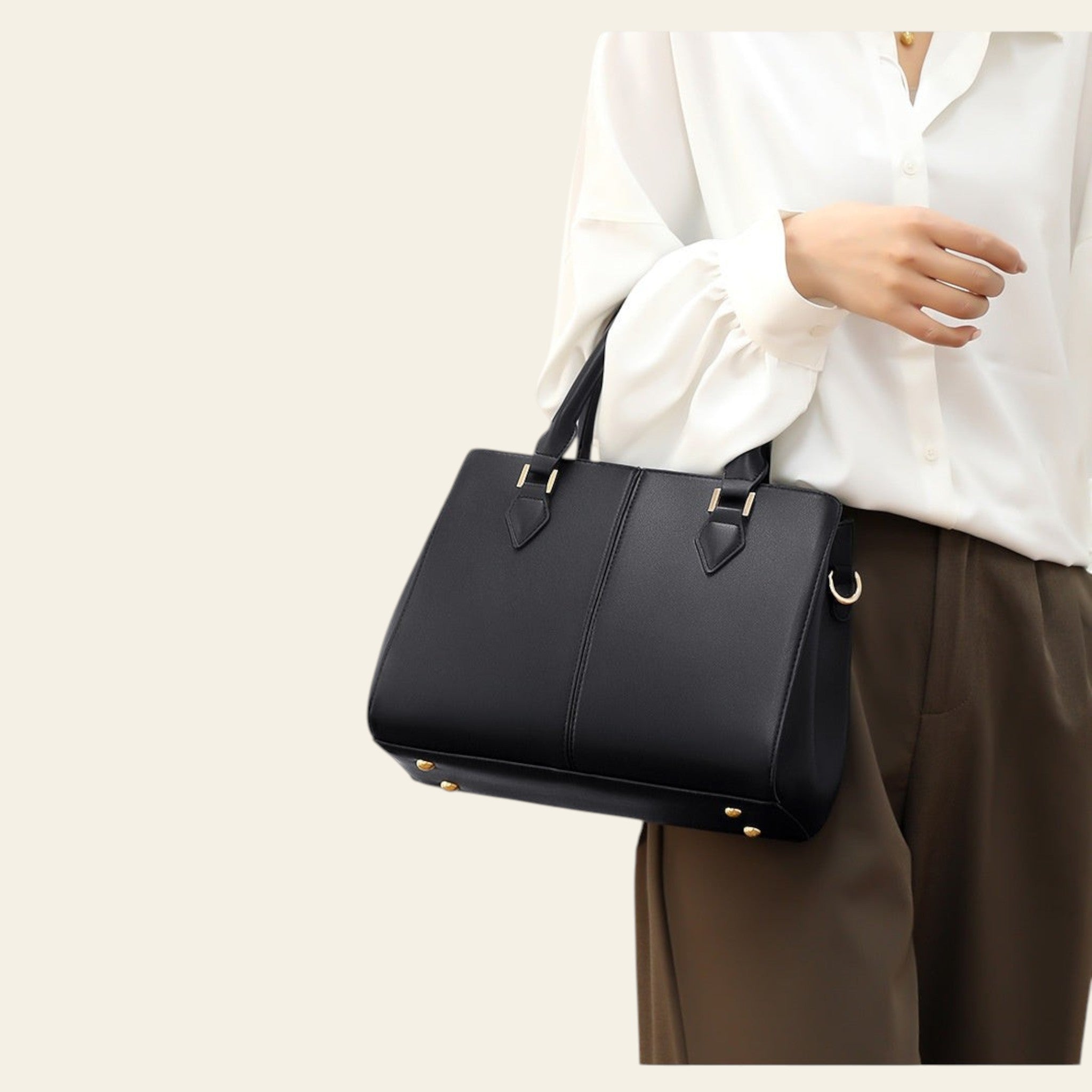 Person holding a black handbag against a neutral background