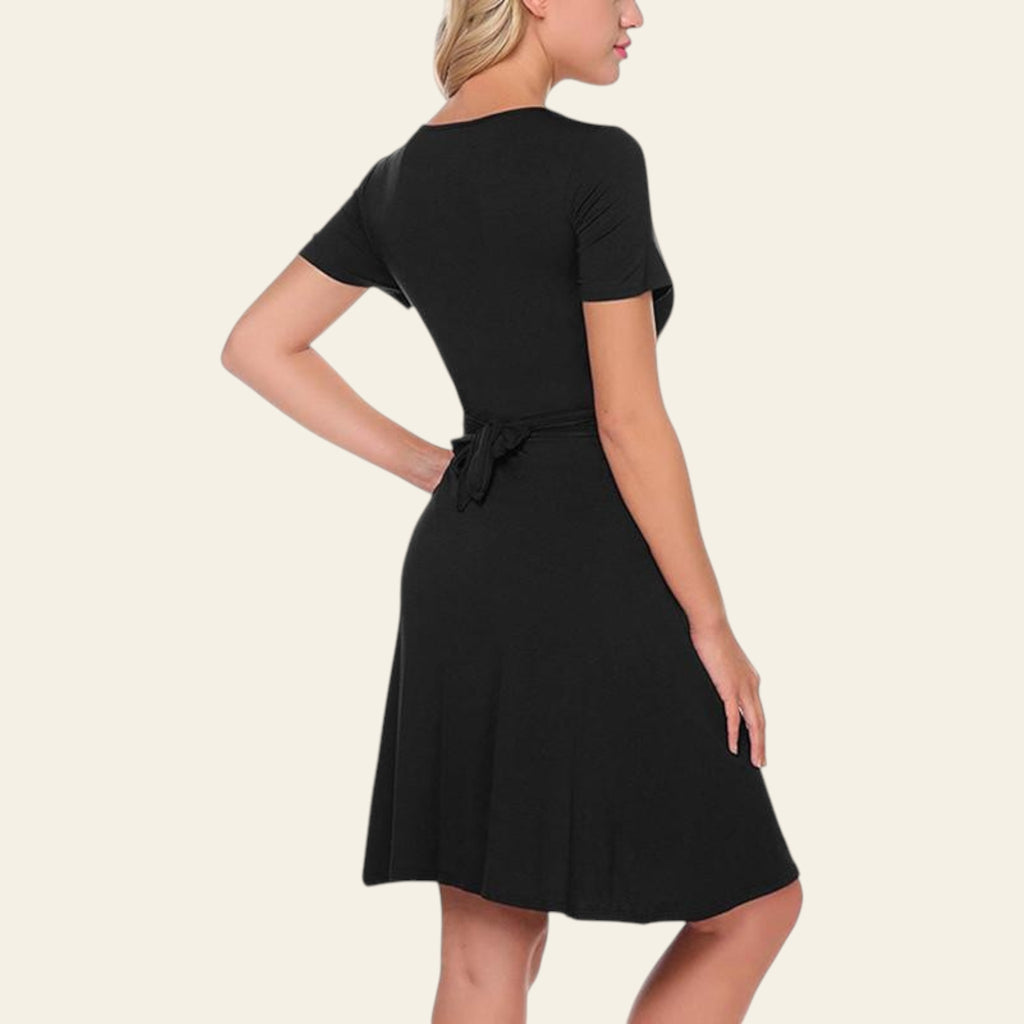 Side view of a woman wearing a black casual short sleeve dress on a white background