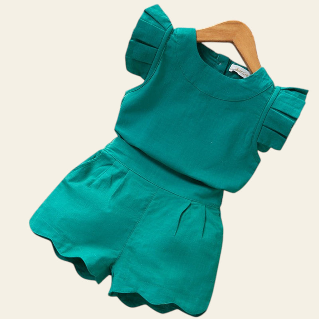 Green ruffled top and shorts set on a wooden surface with a card.