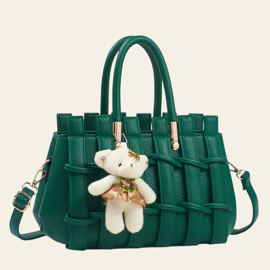 Green handbag with a teddy bear charm on a light background