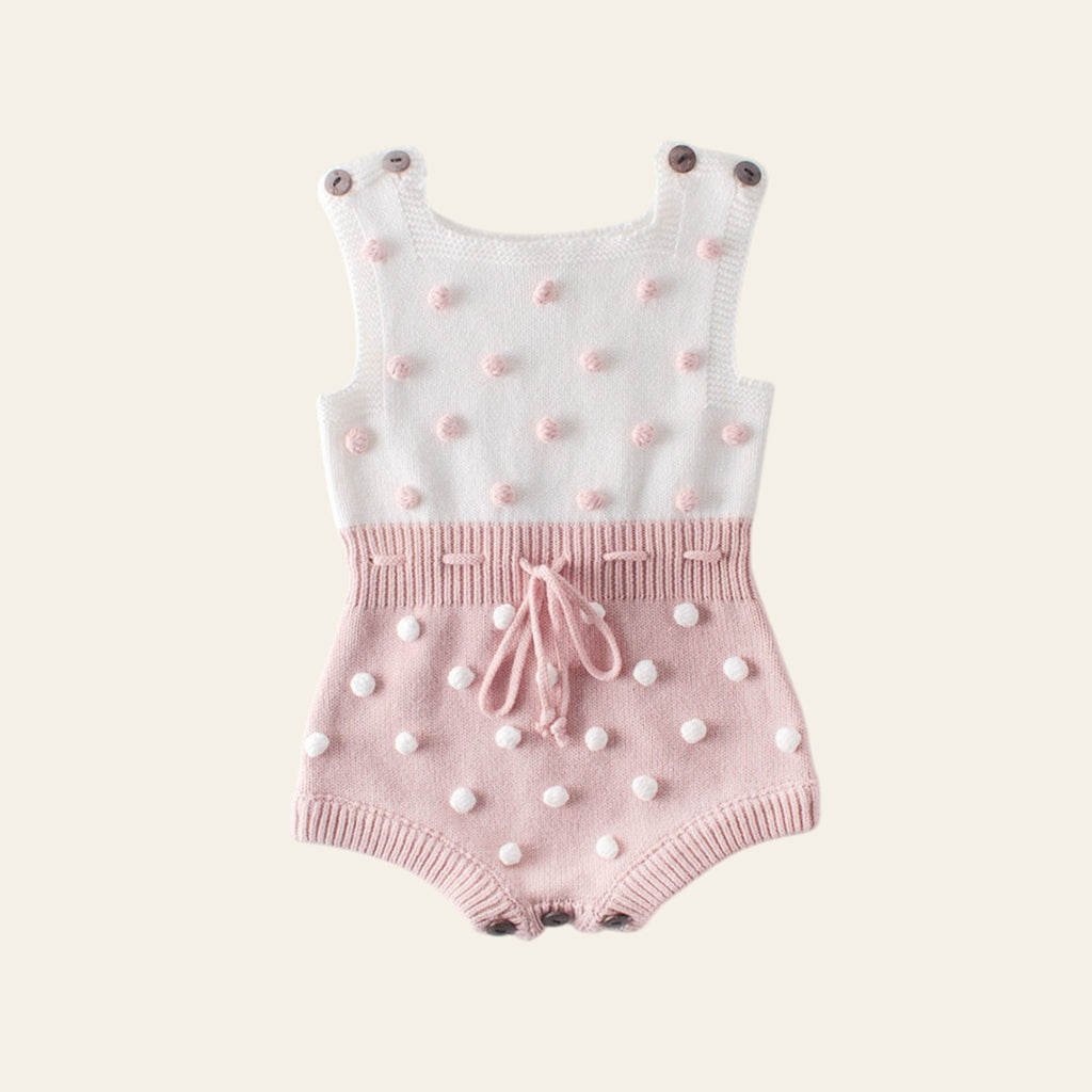 Baby romper with white top and pink shorts featuring polka dots on a light gray background
