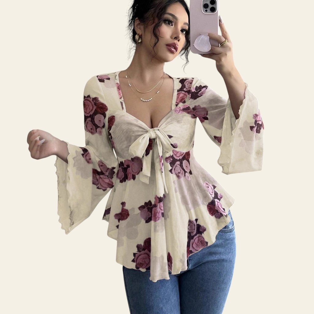 Woman wearing a floral blouse with bell sleeves taking a mirror selfie.