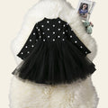 Black polka dot dress with a tulle skirt on a white fur surface.