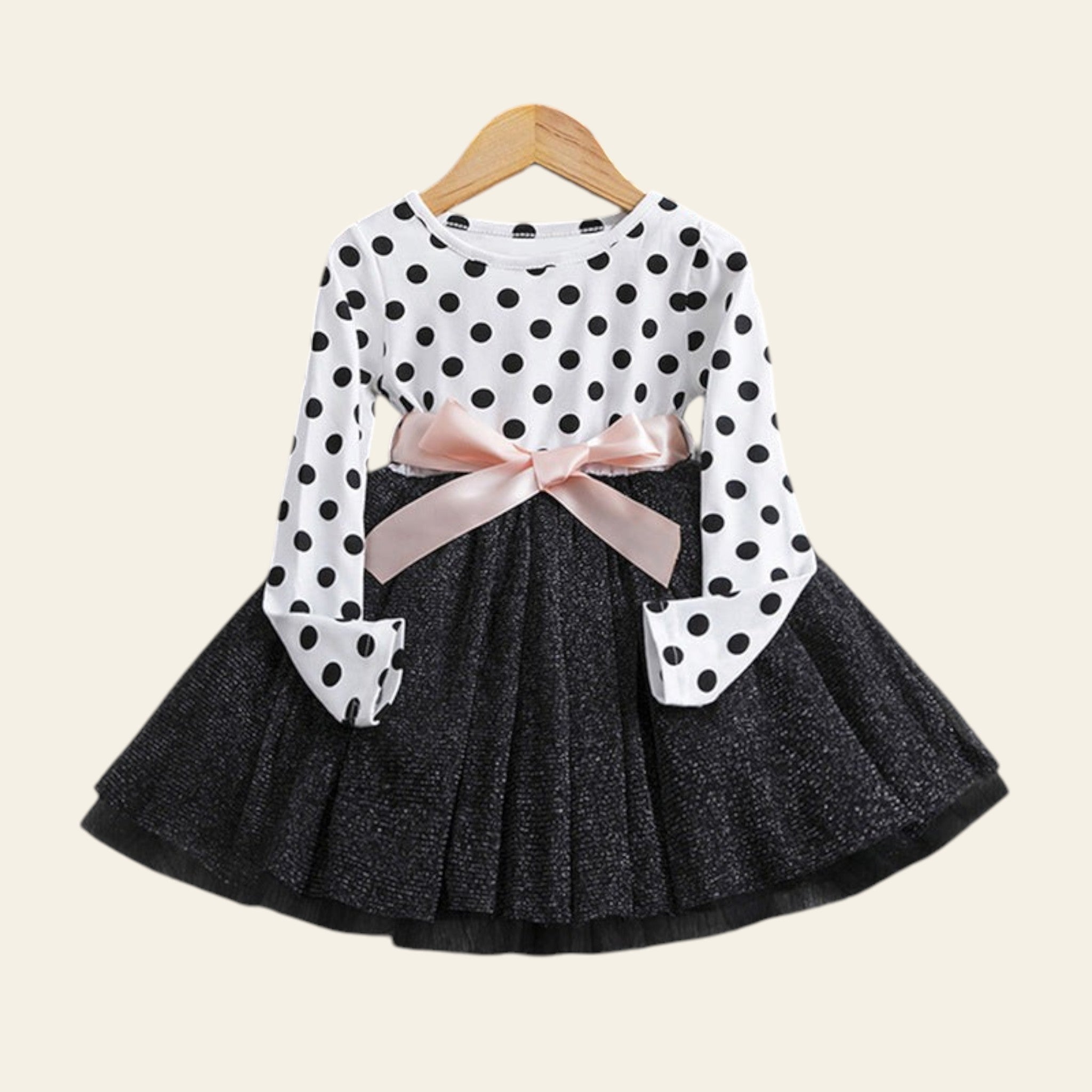 Polka dot blouse with a bow and black skirt on a wooden surface.