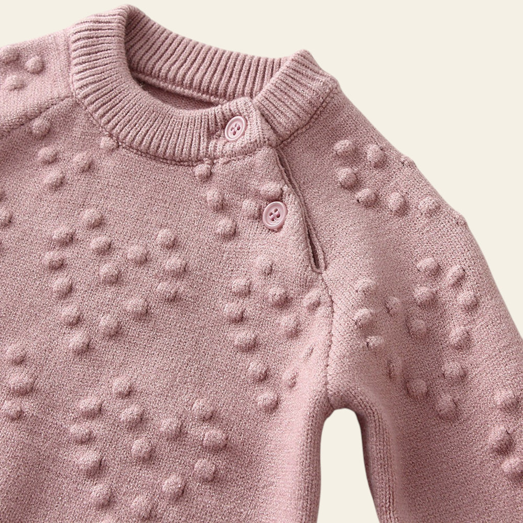 Pink knitted sweater with textured pattern on a light background