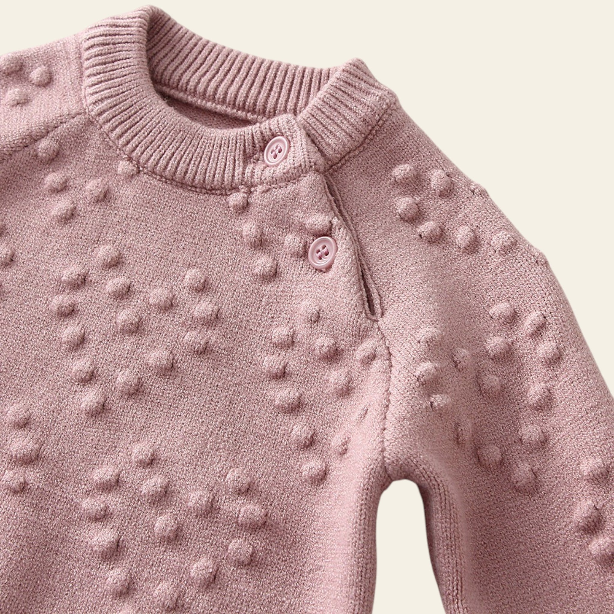 Pink knitted sweater with textured pattern on a light background