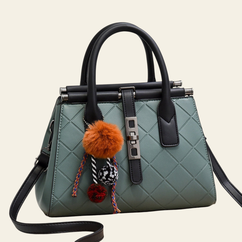 Green handbag with black handles and trim, featuring colorful pom-poms on a white background.