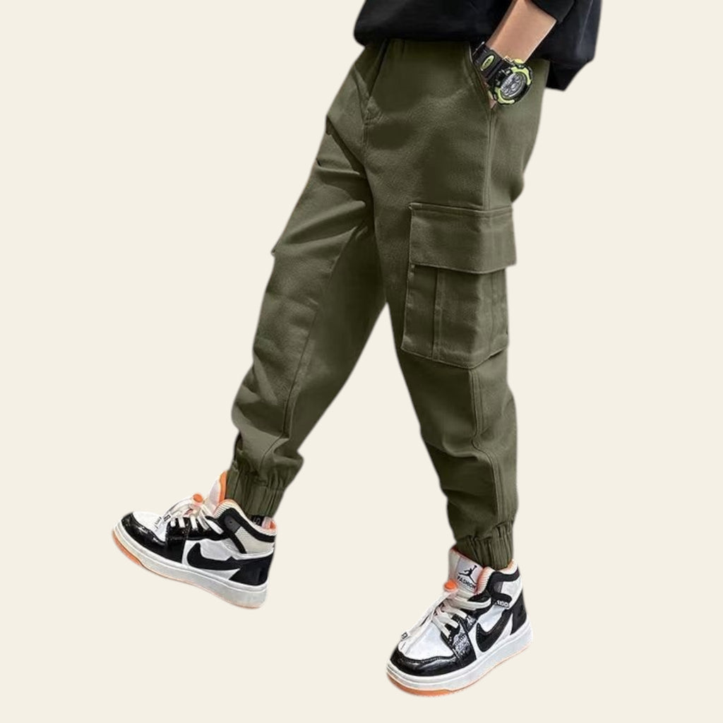 Person wearing green cargo pants and black and white sneakers indoors.