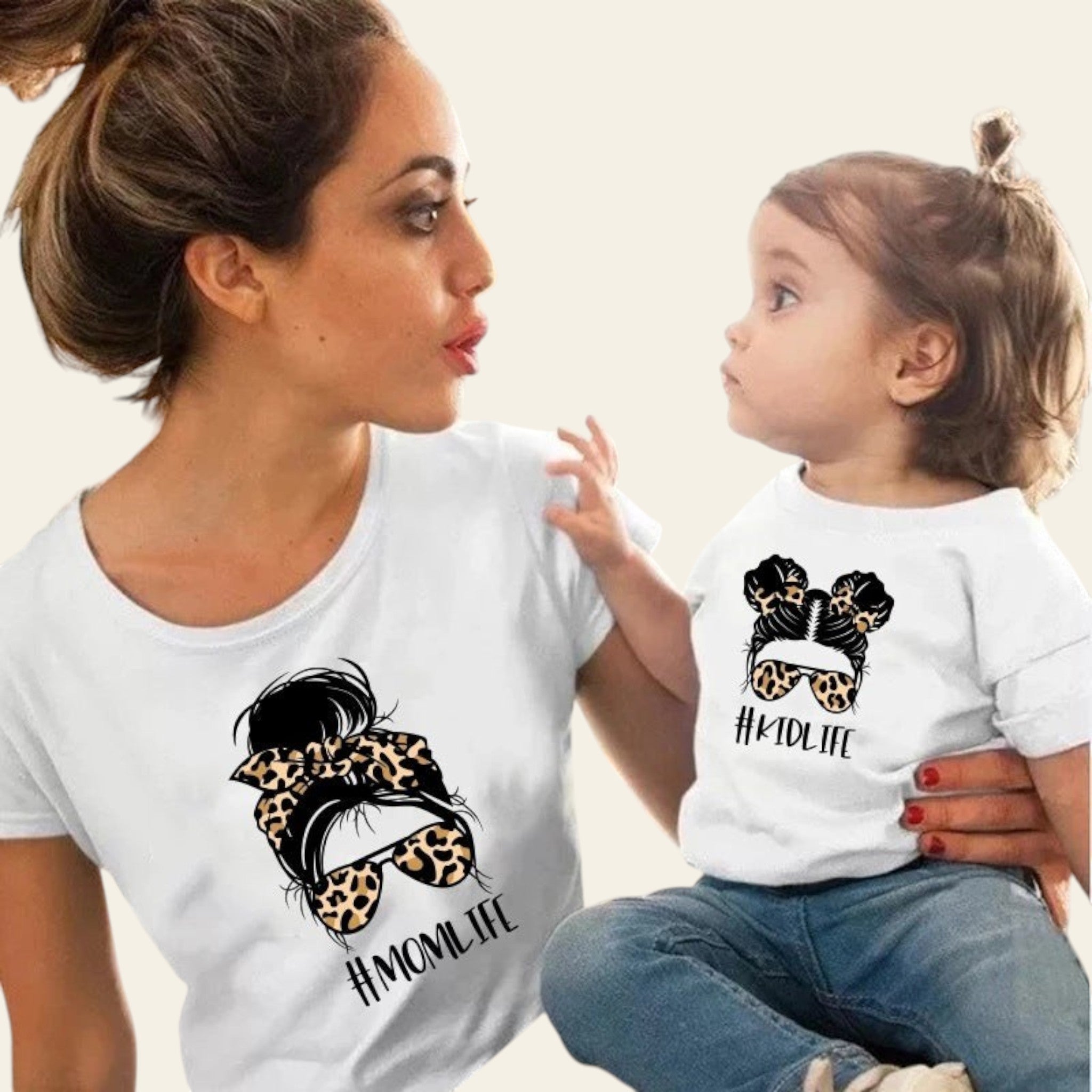 Woman and child wearing matching white t-shirts with a graphic design and text.