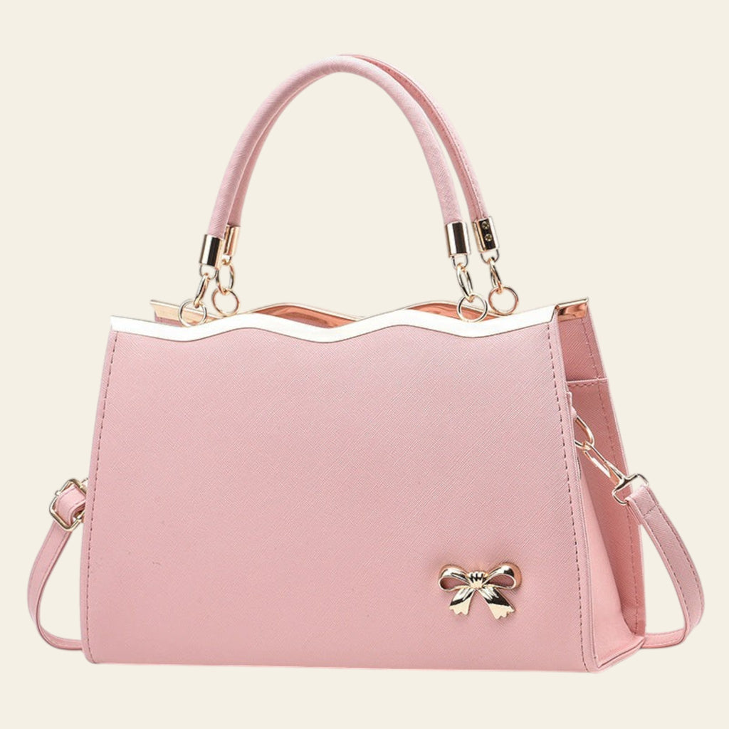 Pink handbag with a gold bow detail on a white background
