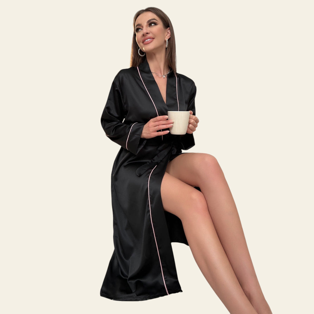 Woman in a black satin robe holding a mug in a cozy room.