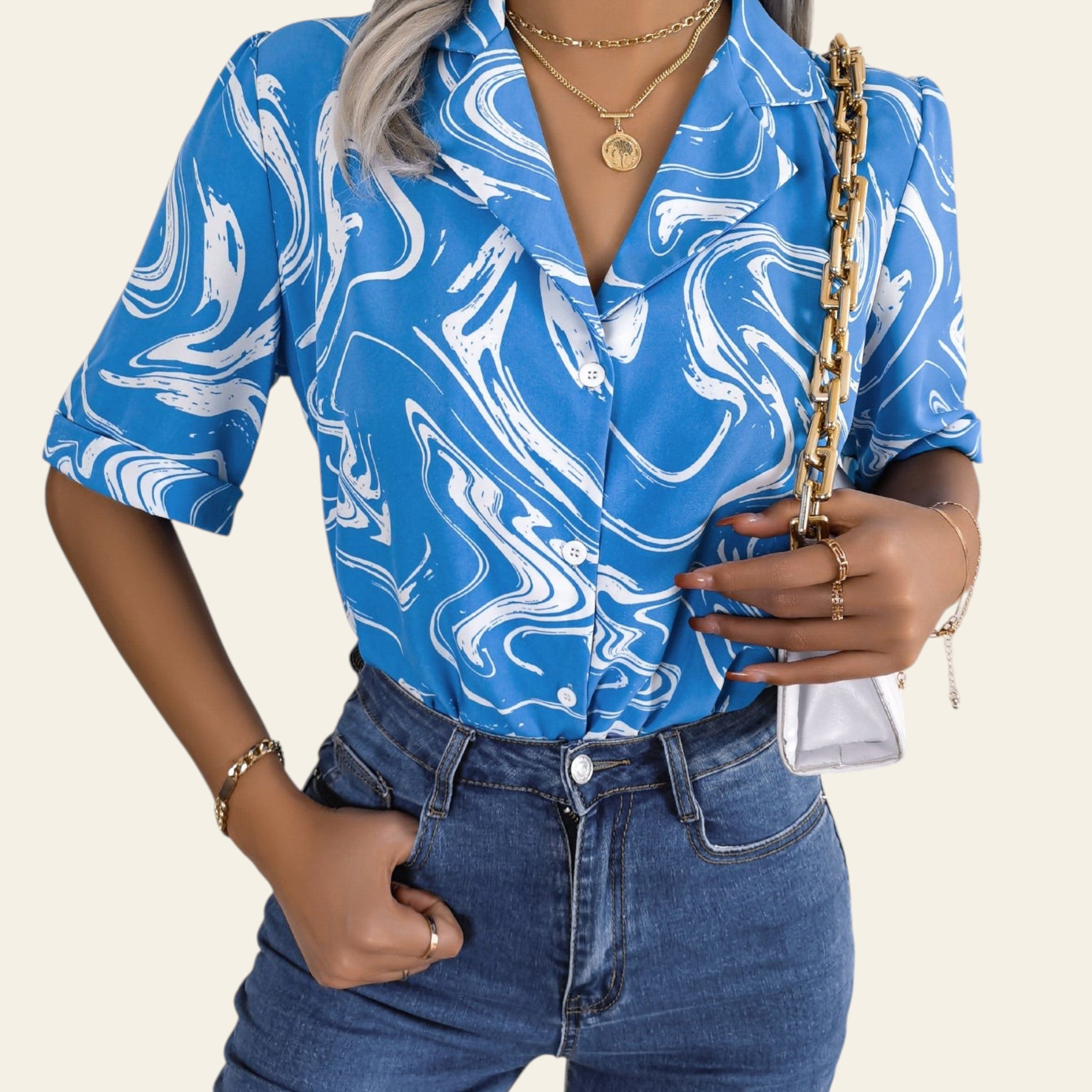 Person wearing a blue and white patterned shirt and blue jeans, holding a gold handbag.
