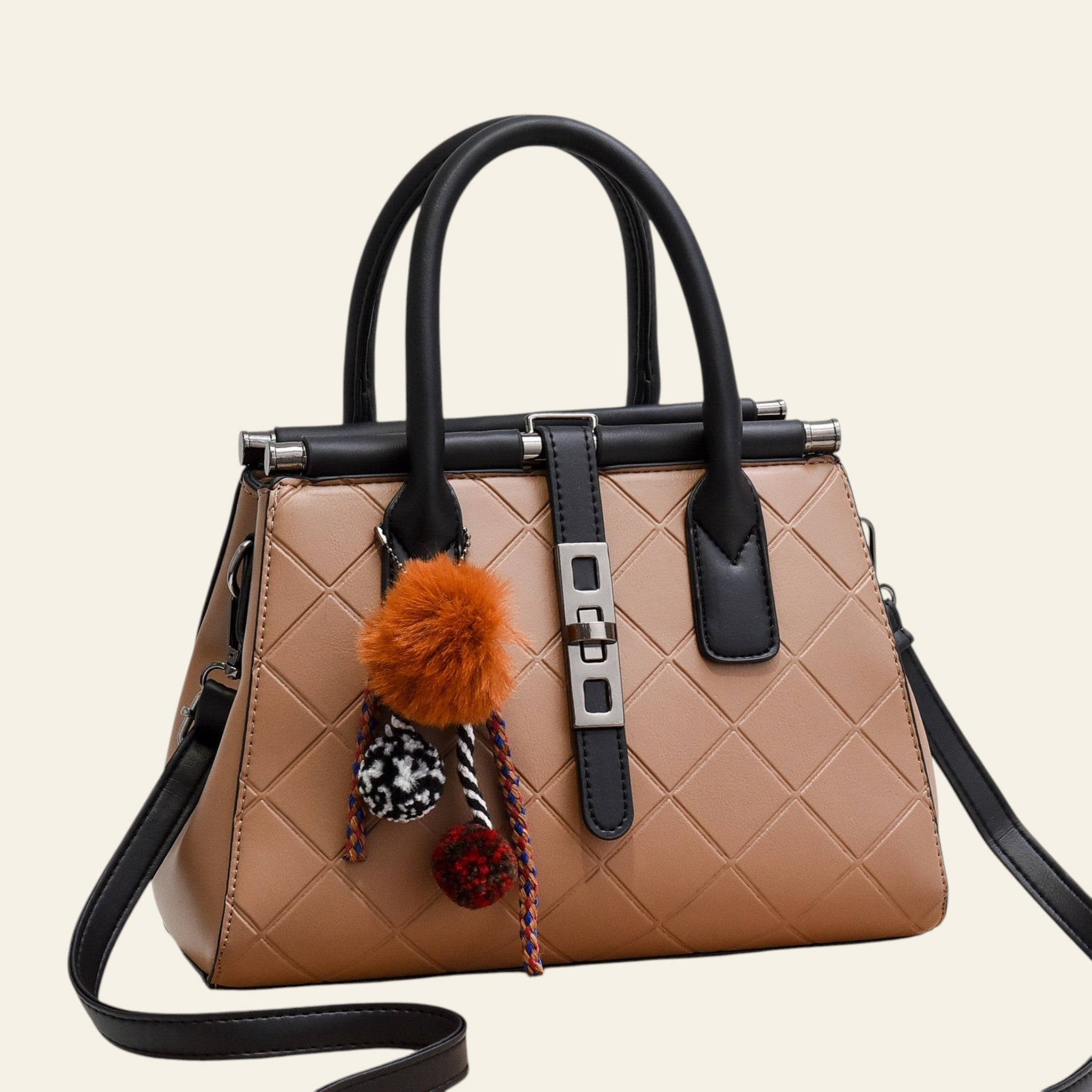 Beige handbag with black handles and strap, featuring decorative pom-poms on a white background.