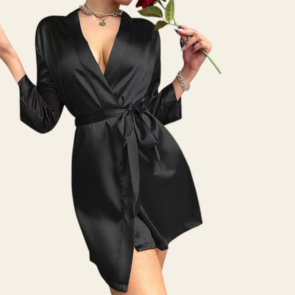 Person wearing a black satin robe holding a red rose against a neutral background