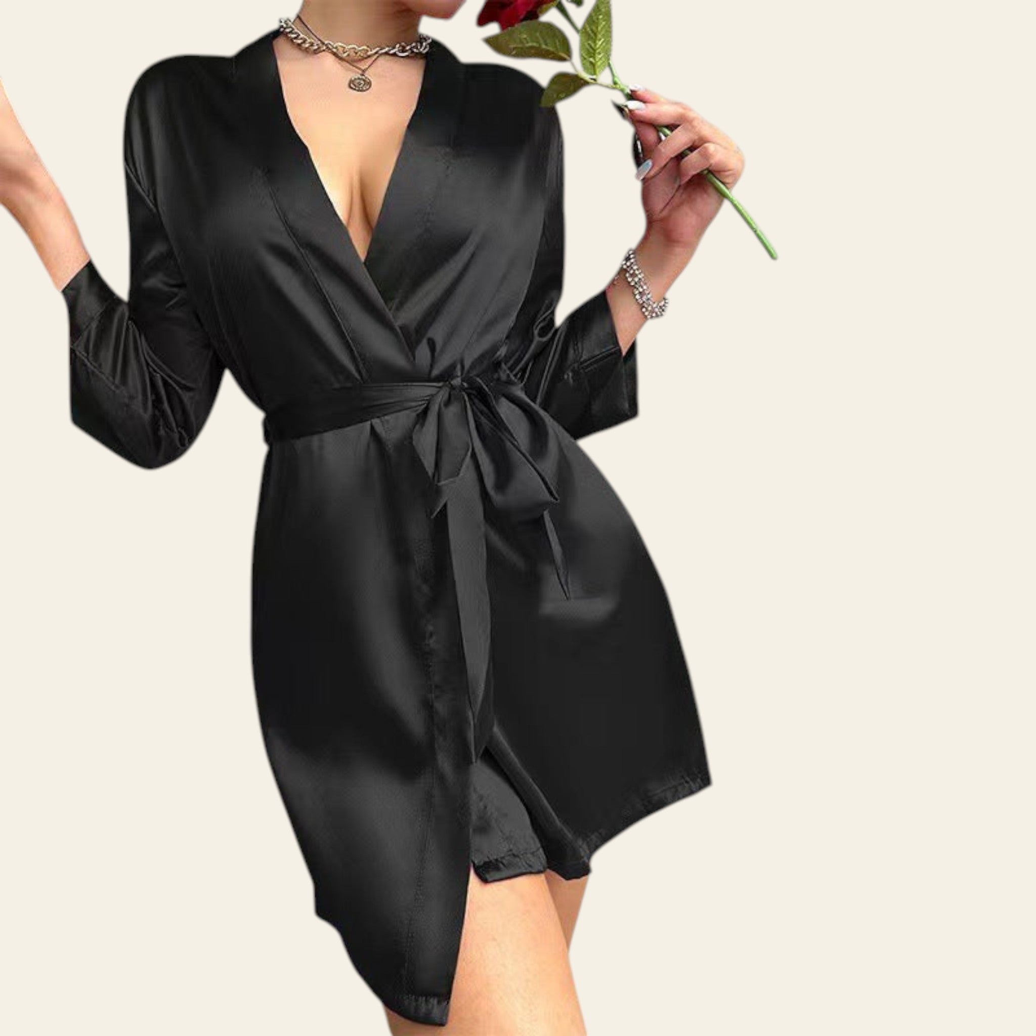 Person wearing a black satin robe holding a red rose against a neutral background