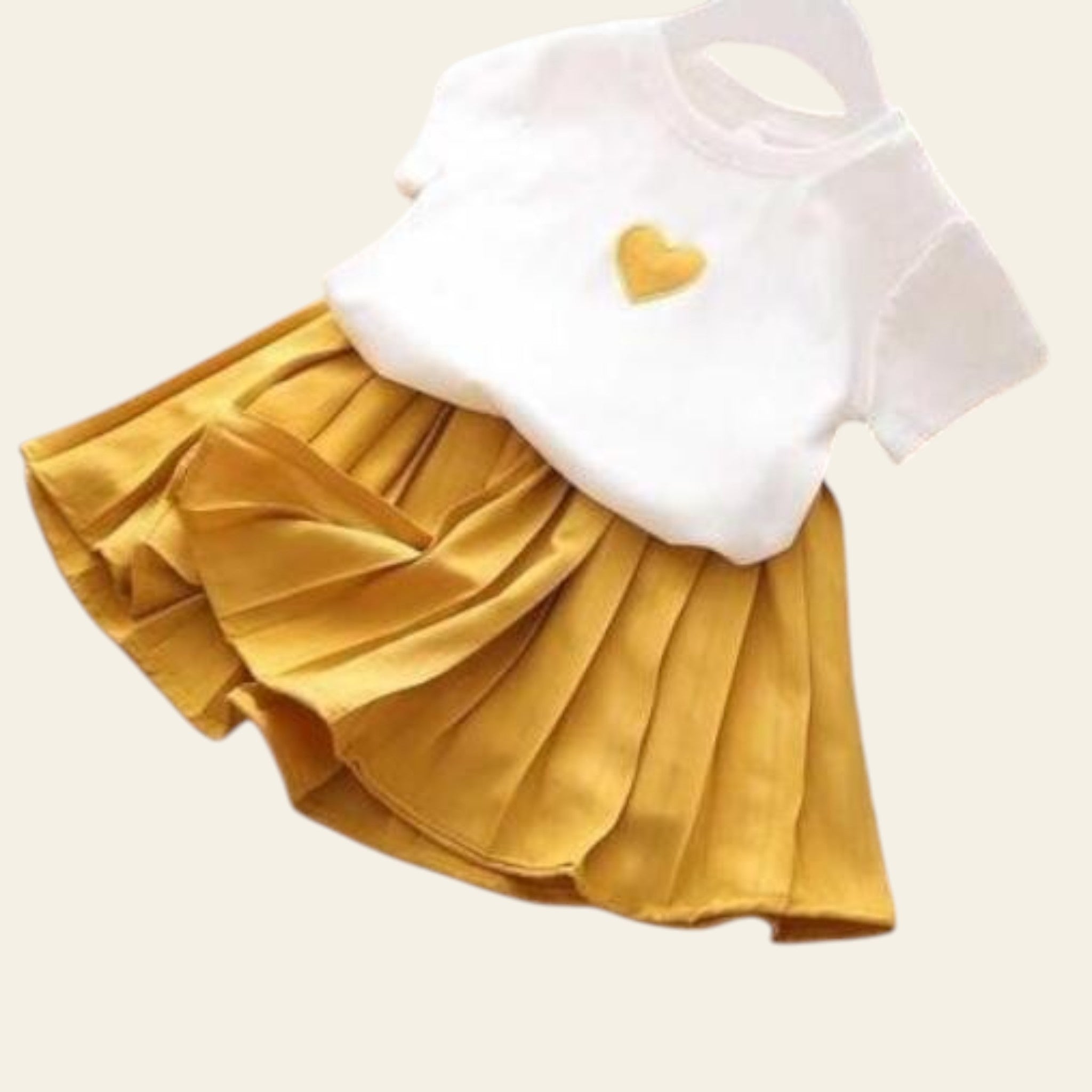 White top with a yellow heart and yellow pleated skirt on a wooden surface