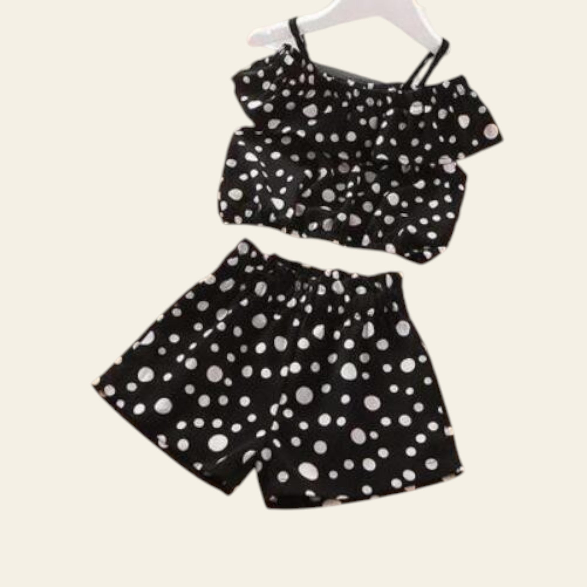 Black and white polka dot top and shorts set on a wooden surface.