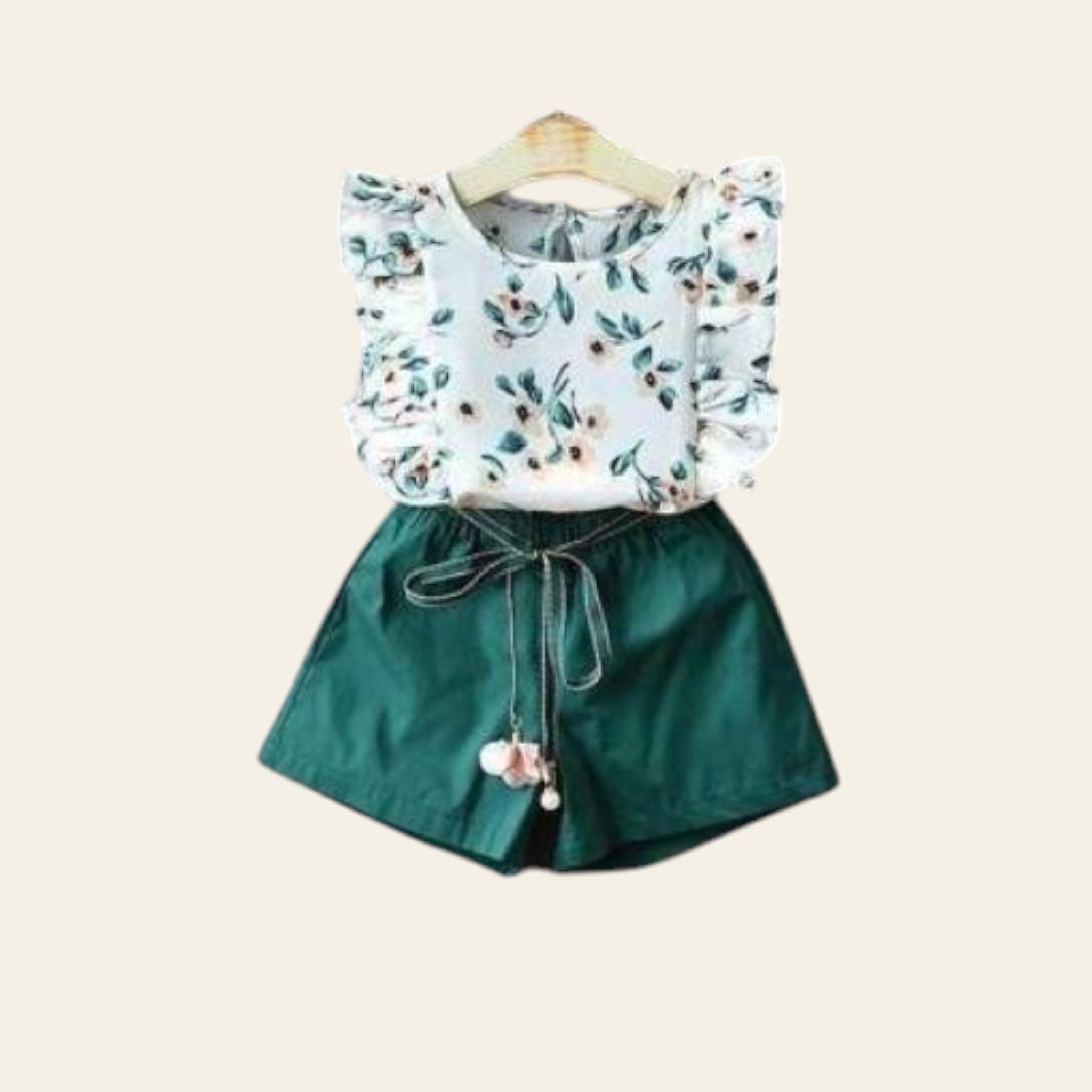 Children's outfit with floral top and green shorts on a gray background