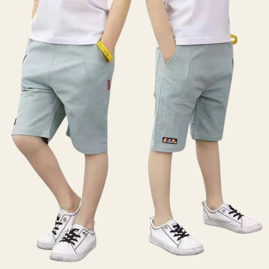Two pairs of legs wearing light gray shorts and white sneakers on a street.