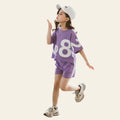 Child wearing a purple outfit with large numbers, standing on a concrete floor.