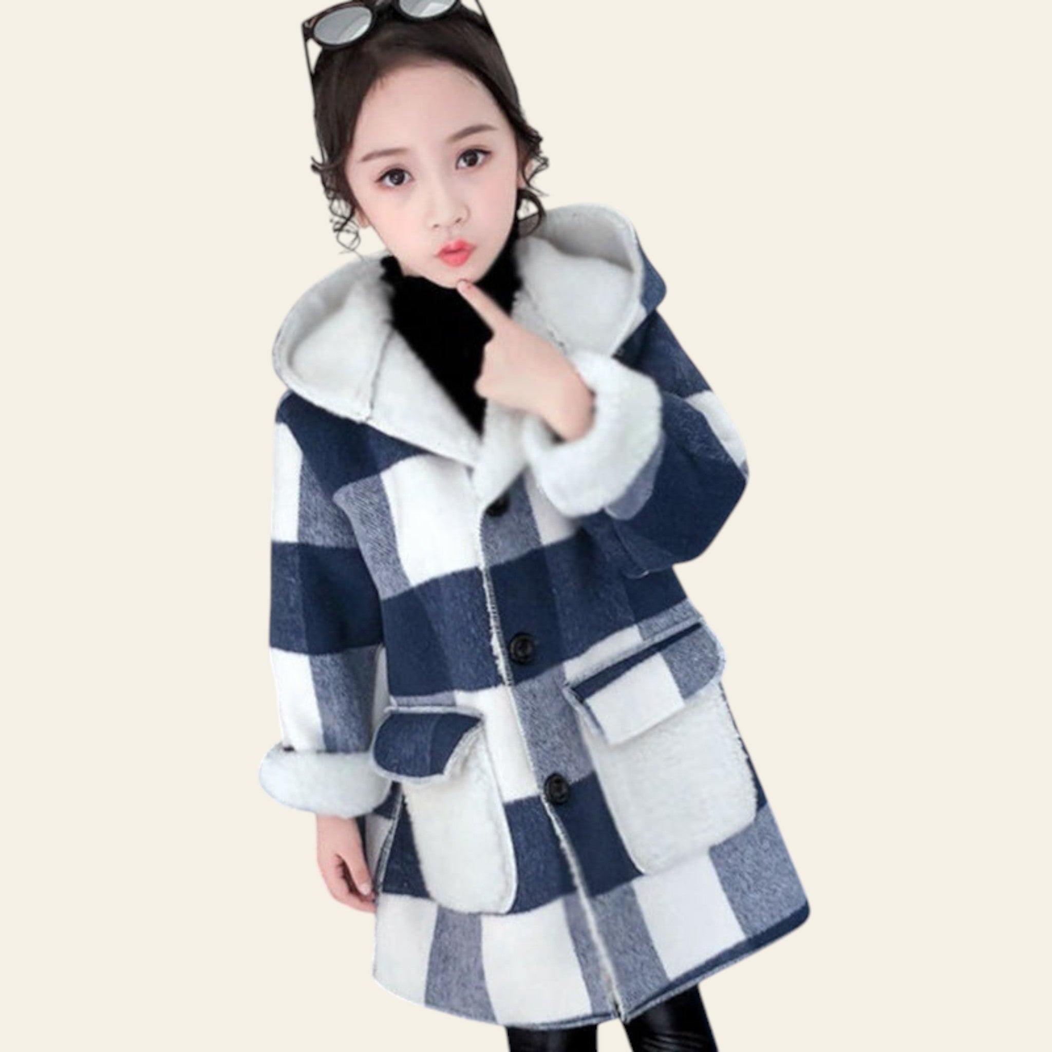 Child wearing a blue and white checkered coat with fur trim, sitting on a blue chair.
