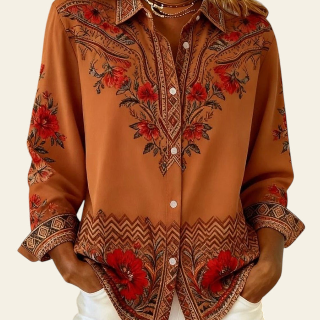 Person wearing a patterned shirt with red floral designs on a neutral background