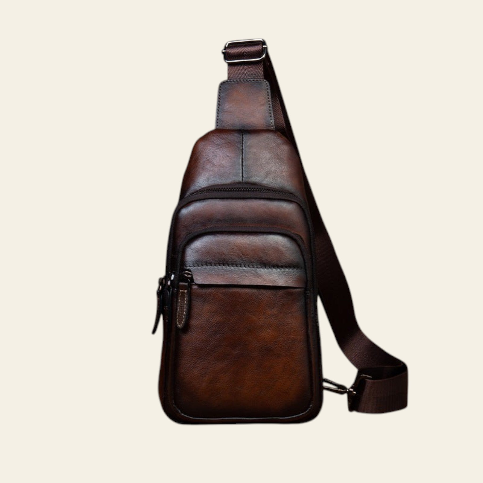 Brown leather sling bag on a wooden surface with a rustic background