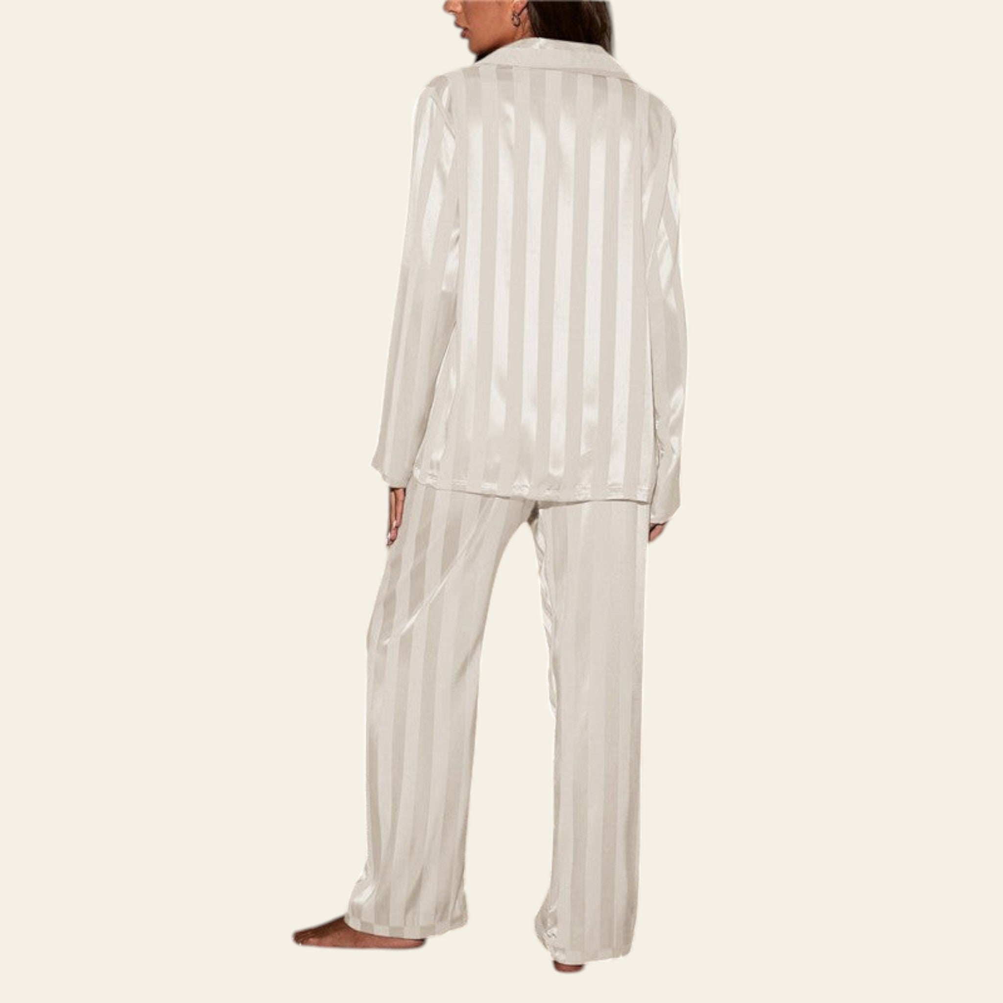 Person wearing a white striped pajama set in a room with gray walls and a patterned rug.
