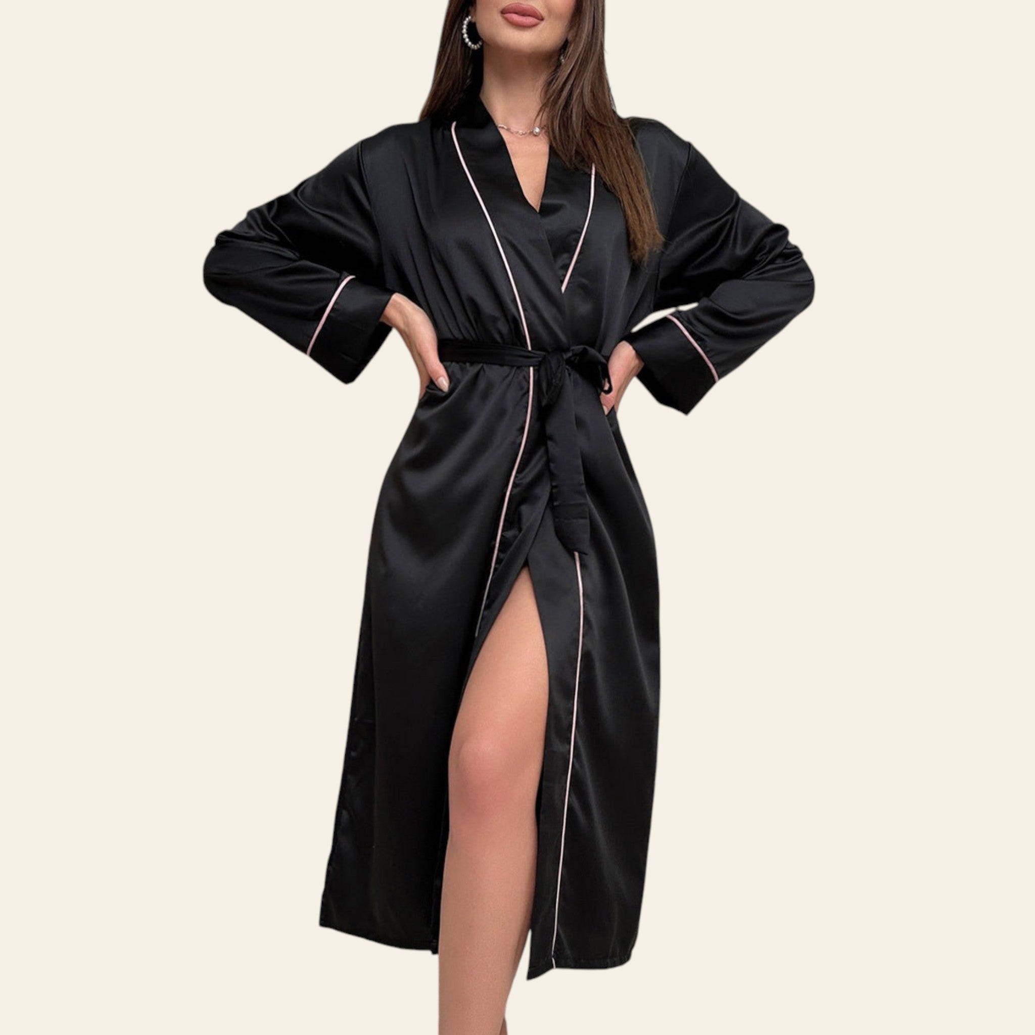 Woman wearing a black satin robe with white piping in a room with large windows.