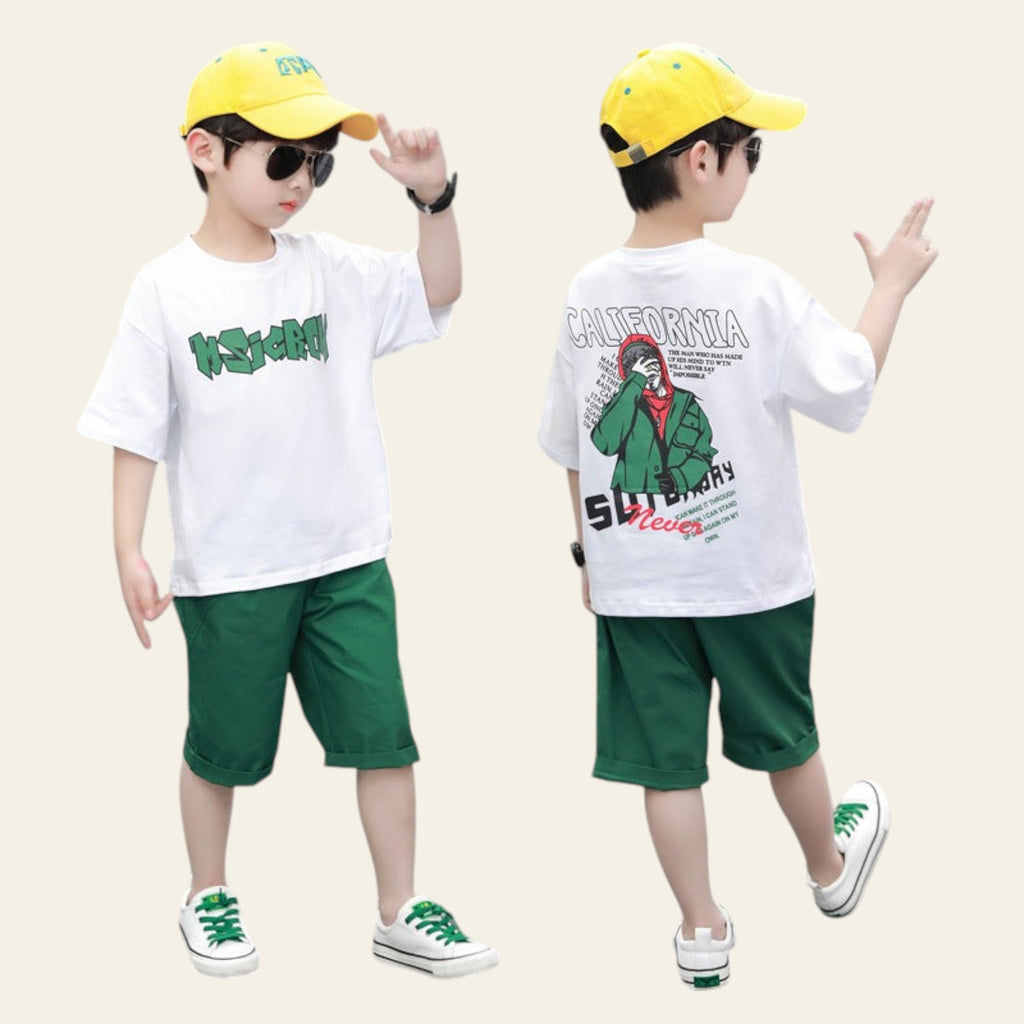 Two children wearing matching outfits with white t-shirts, green shorts, and yellow caps on a street.