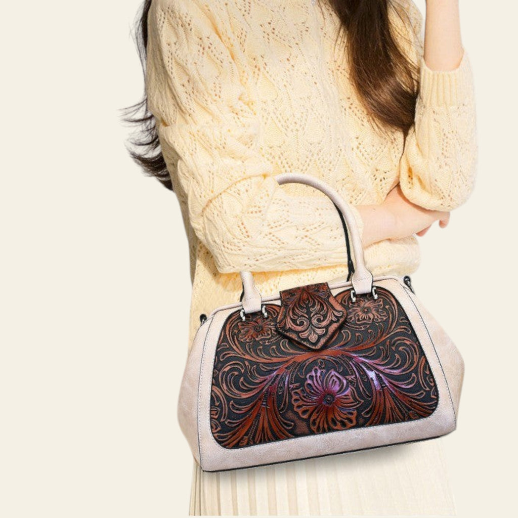 Person wearing a white sweater holding a handbag with intricate floral patterns.