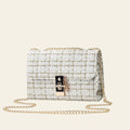 White textured handbag with gold chain on a light gray background