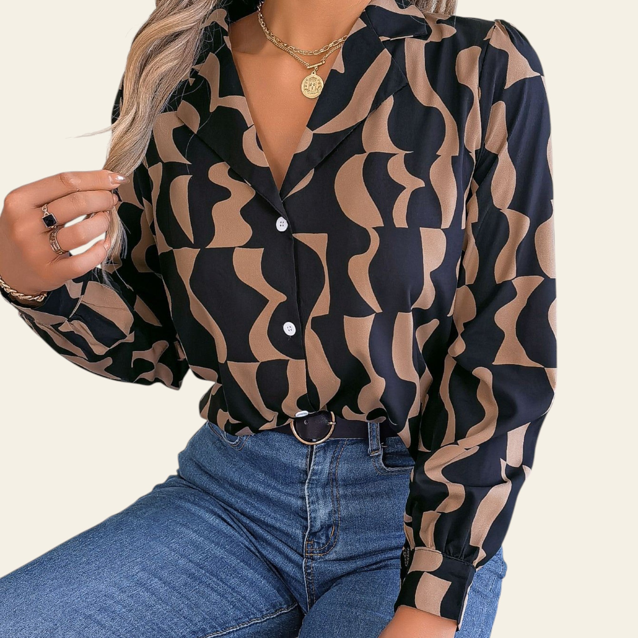 Woman wearing a patterned blouse and jeans sitting on a couch.