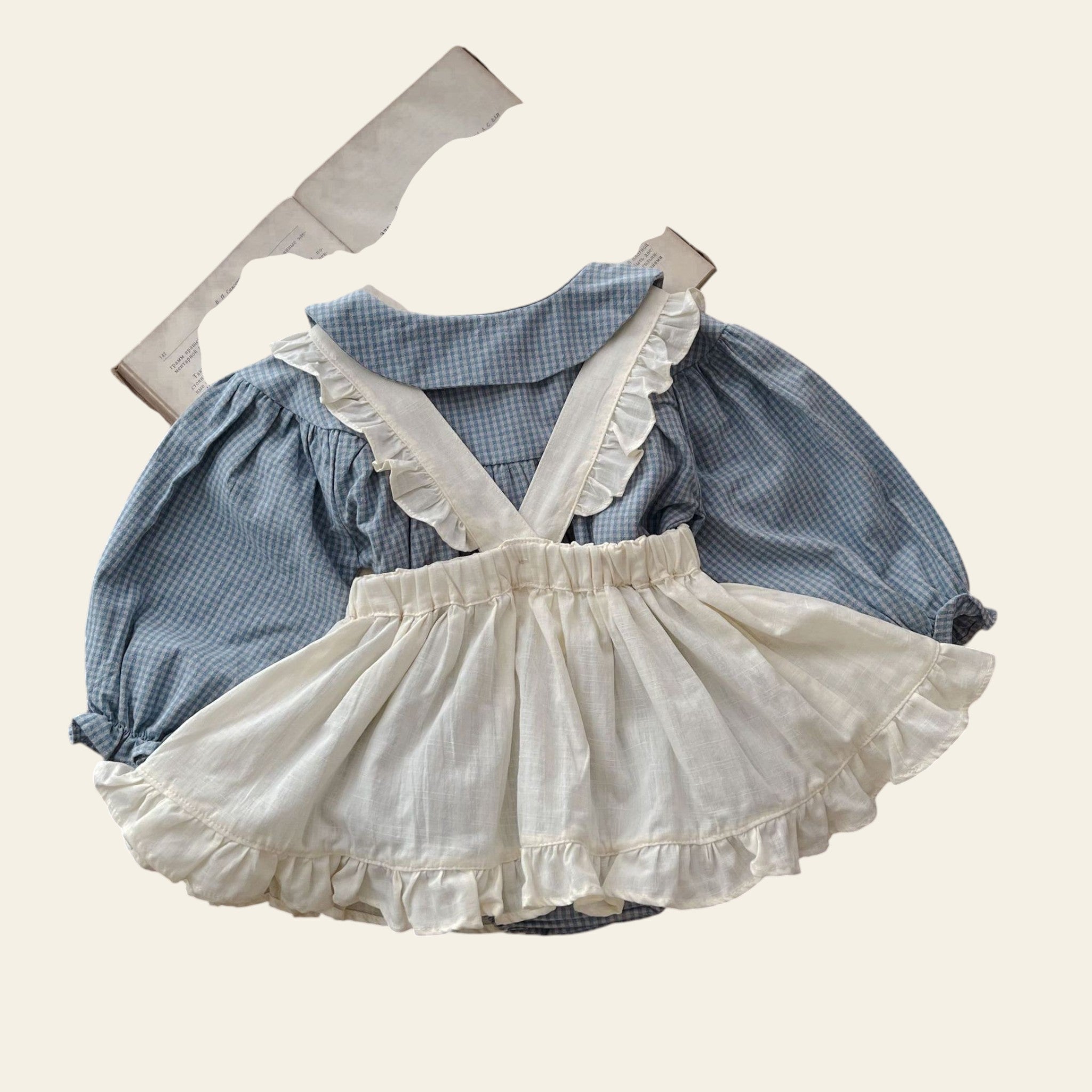 Children's blue checkered dress with white ruffled skirt on a wooden surface.