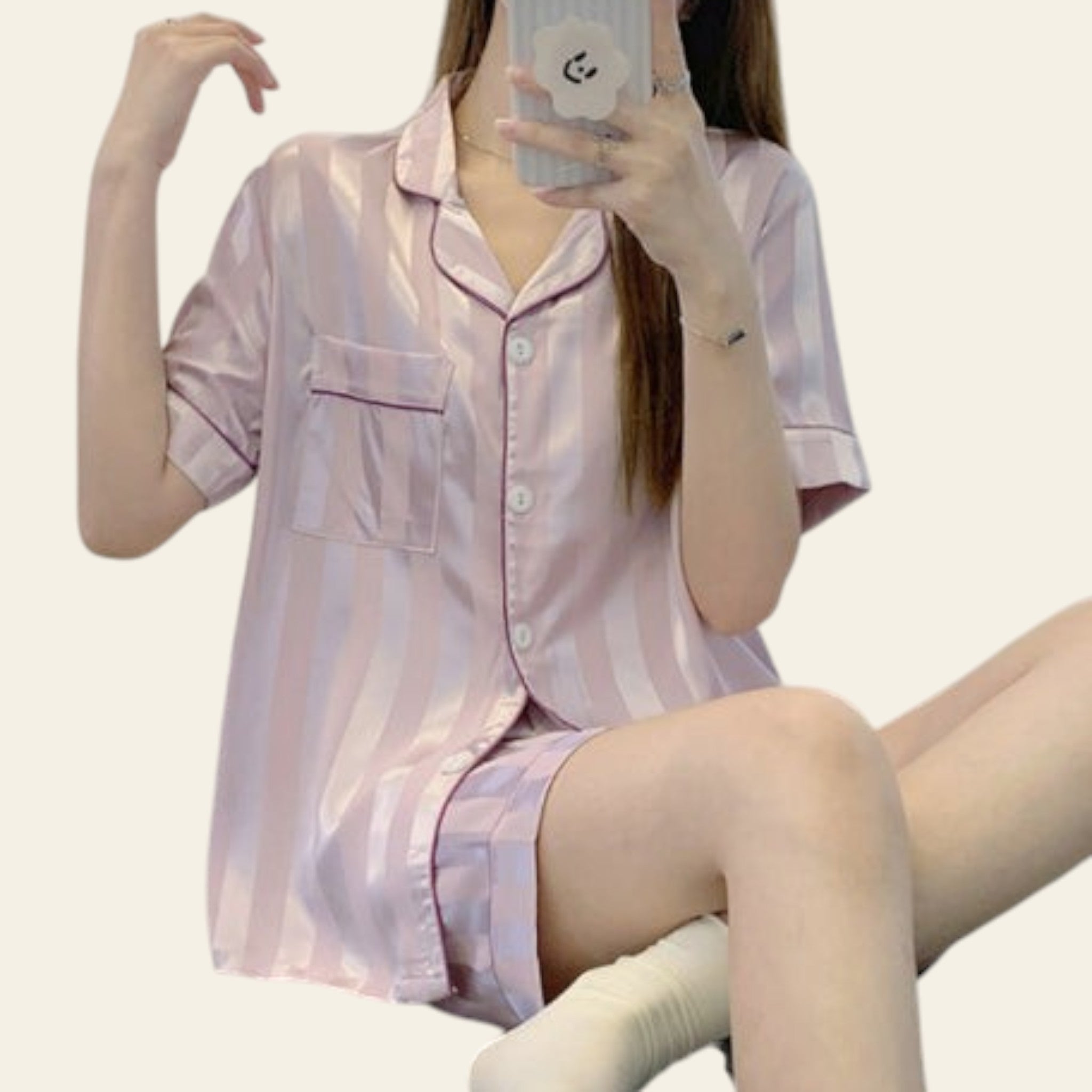 Person wearing a pink striped pajama set sitting on a bed.