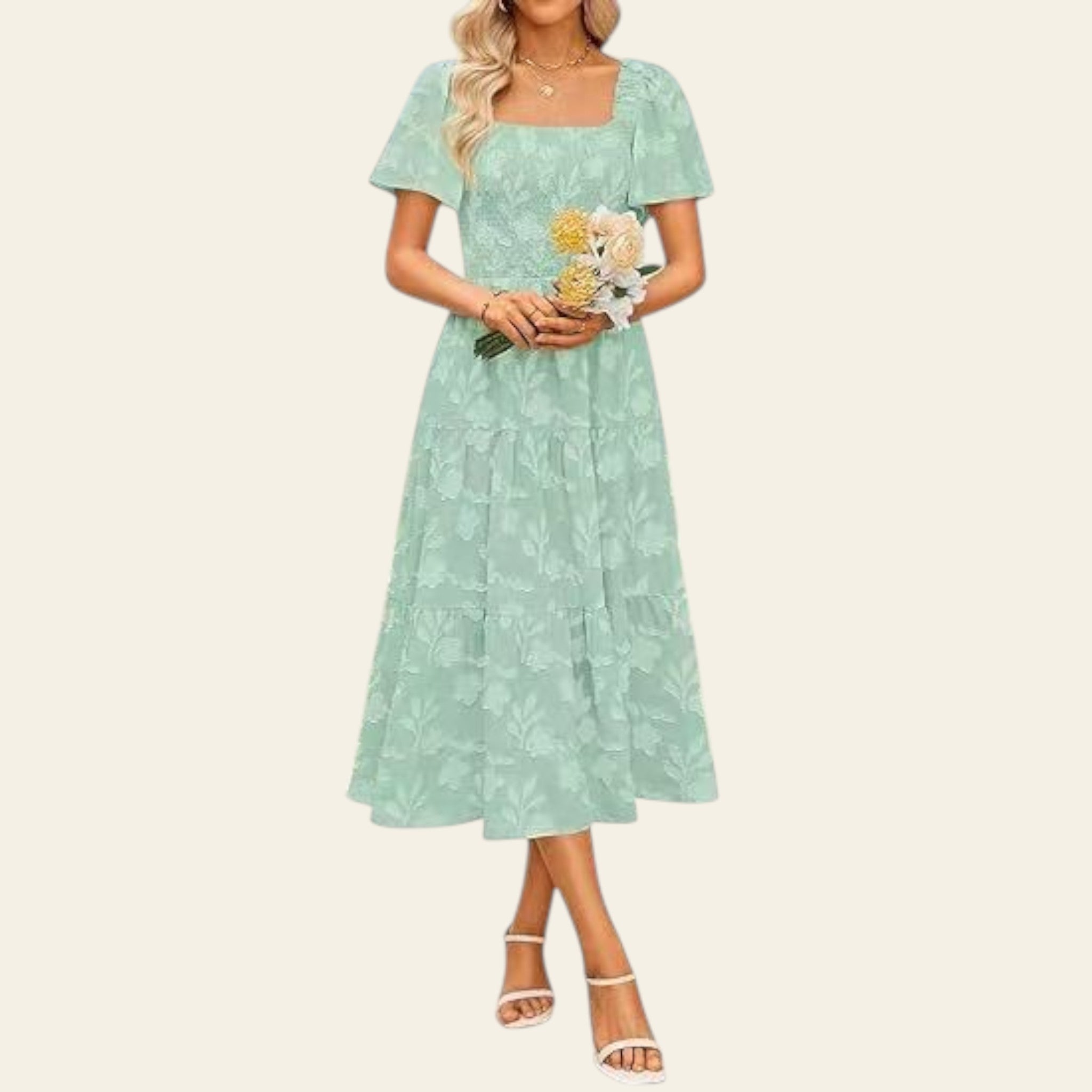 Woman in a light green dress holding a bouquet of flowers with a blurred background
