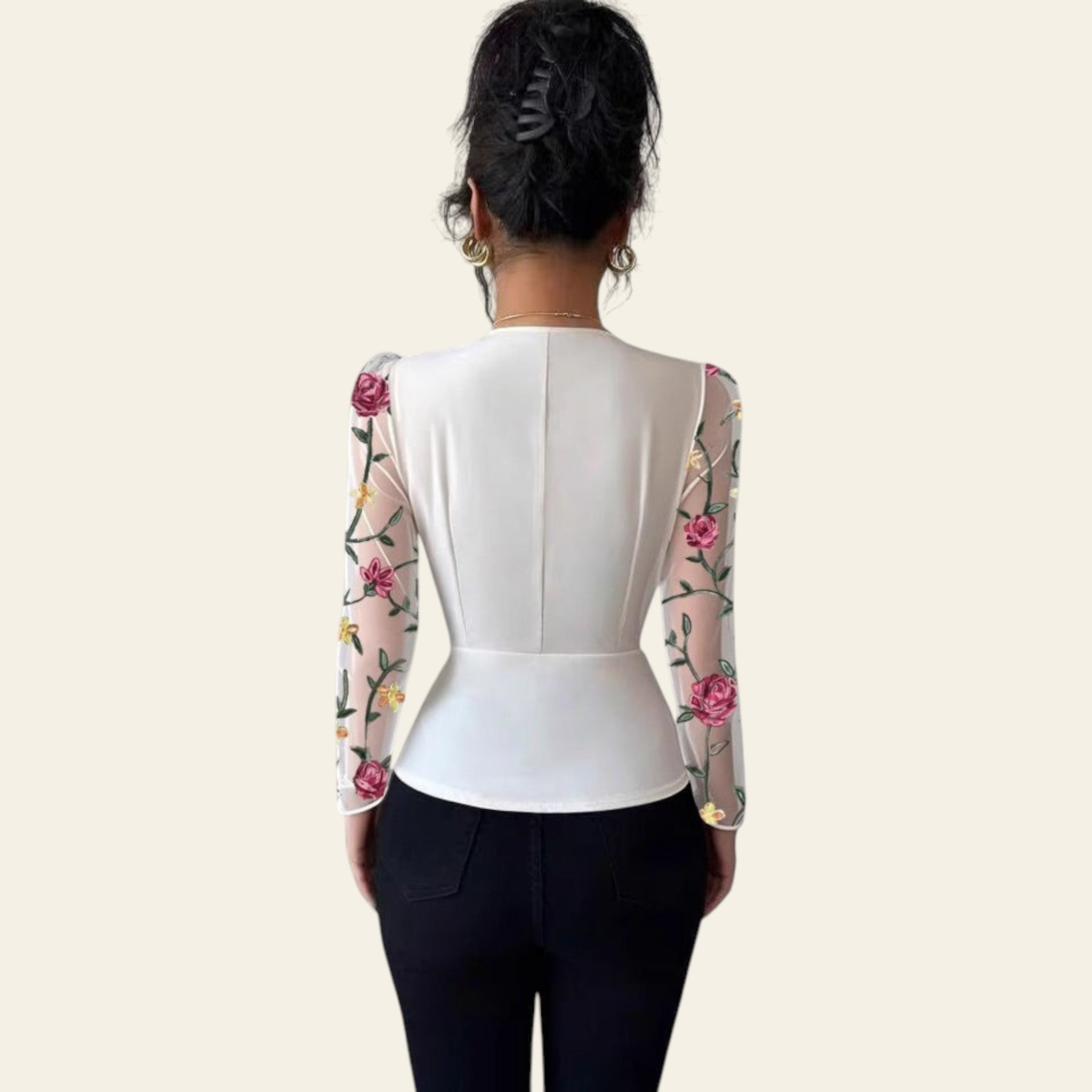 Person wearing a white blouse with floral sleeves against a plain background