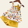 Colorful polka dot dress with a yellow bow and matching shorts on a wooden surface.