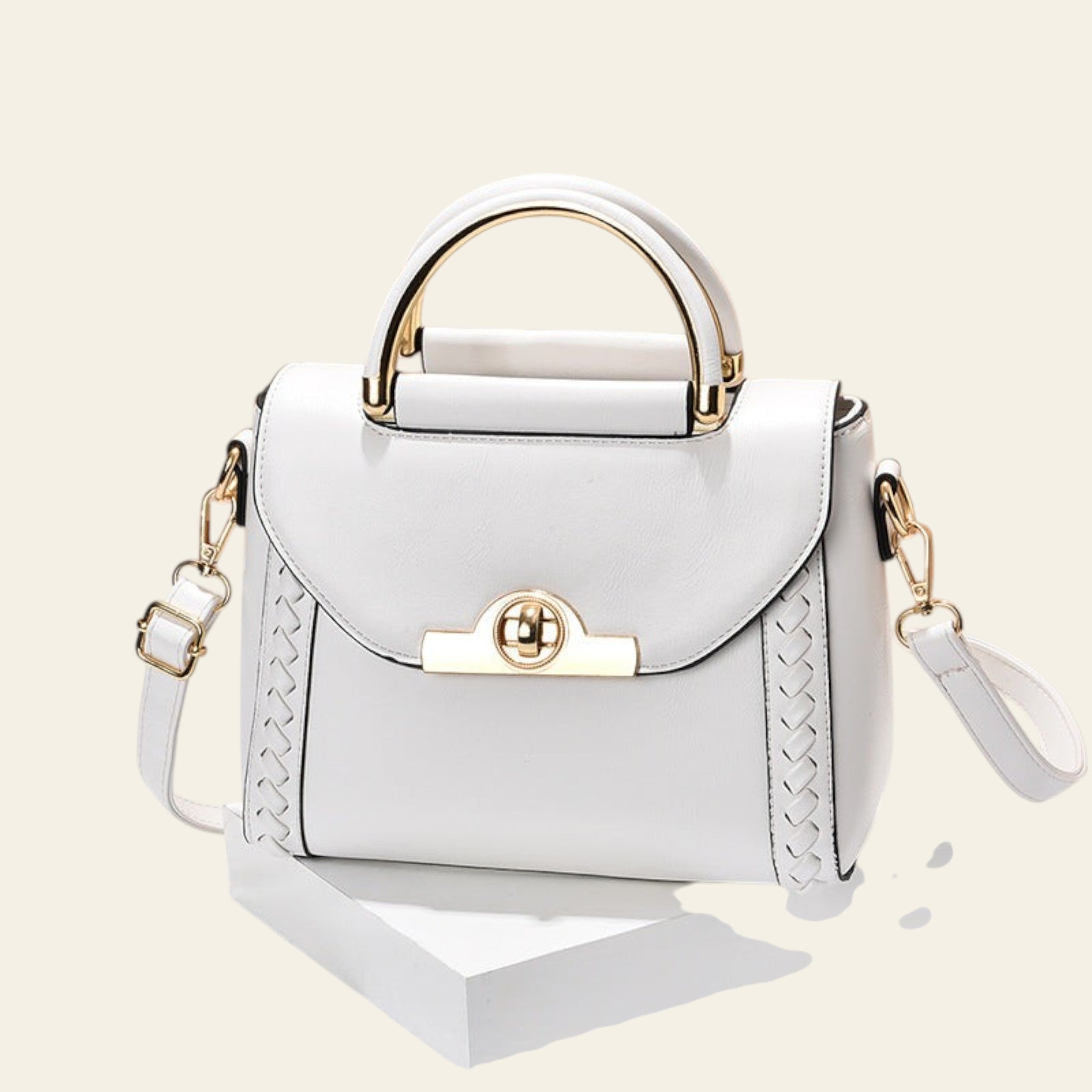 White handbag with gold accents on a beige background