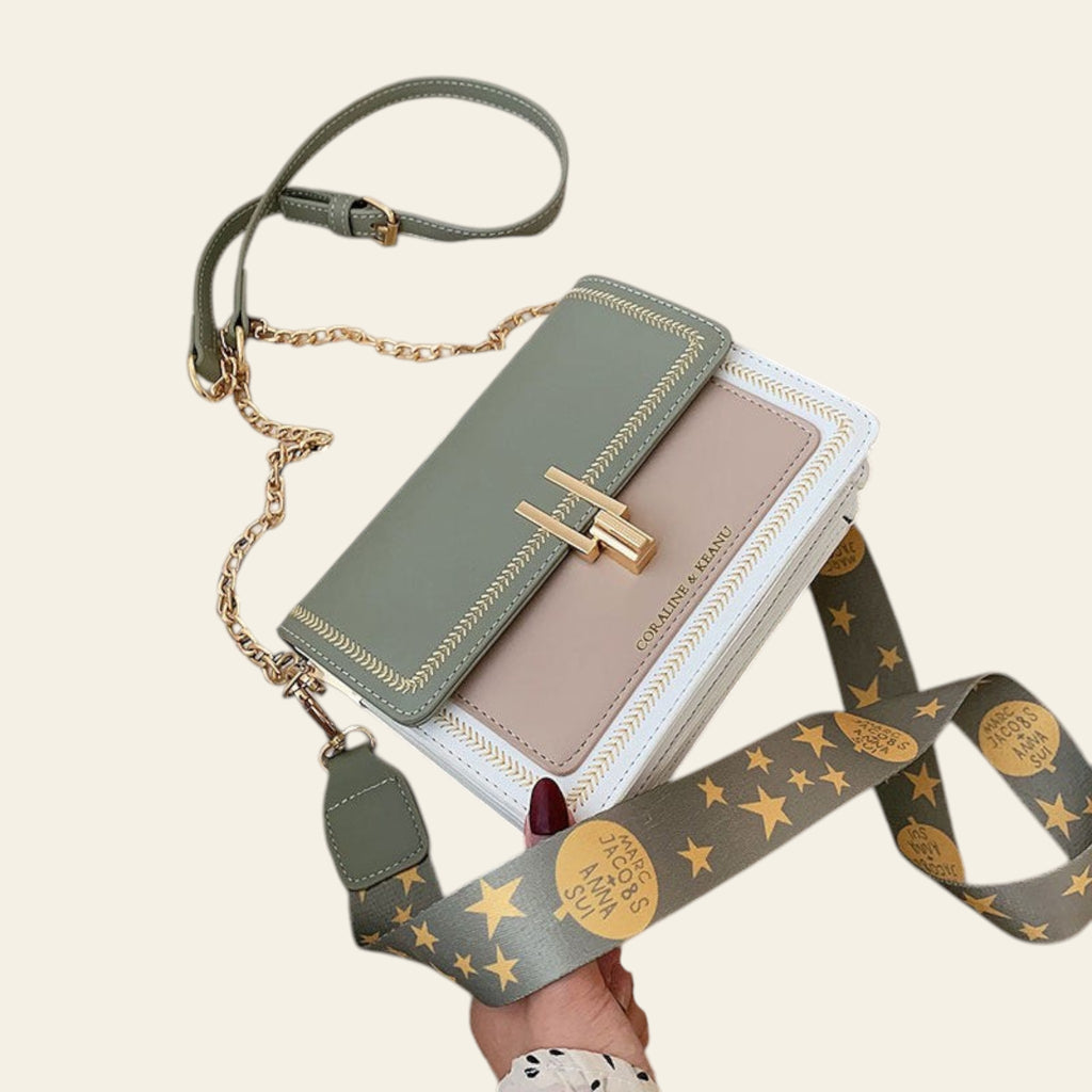 Green handbag with star-patterned strap on a beige surface