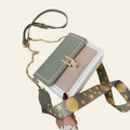 Green handbag with star-patterned strap on a beige surface