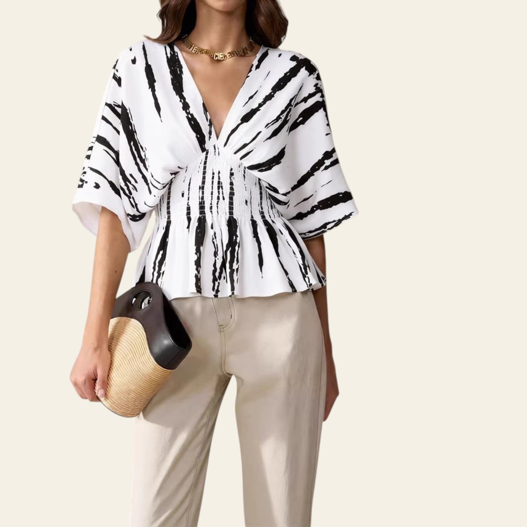 Woman wearing a black and white patterned blouse with a beige background