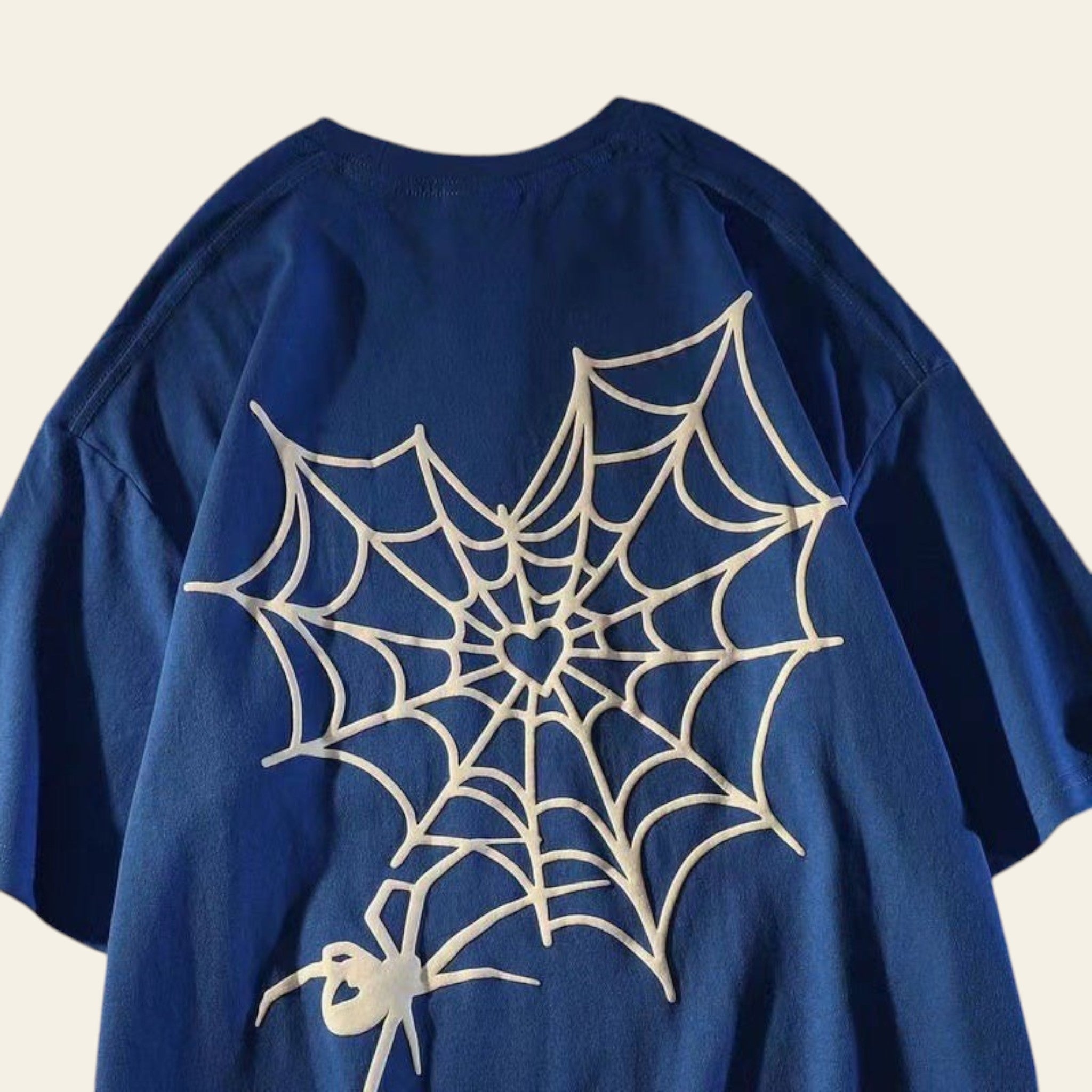 Blue shirt with white spider web design on a textured surface