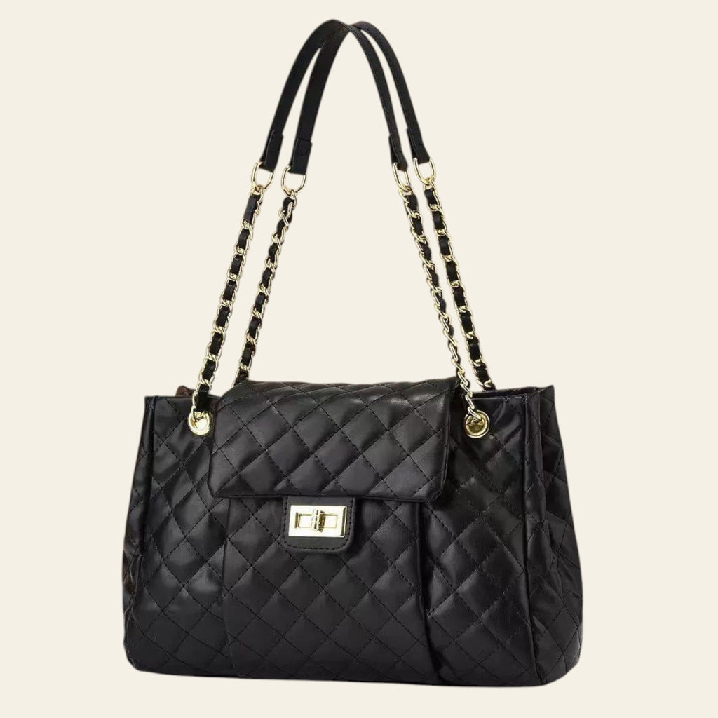 Black quilted handbag with chain straps on a beige background