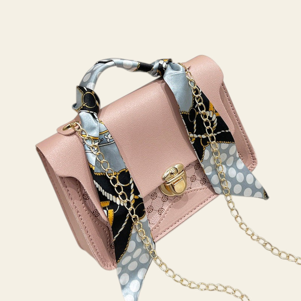 Pink handbag with a patterned strap on a fluffy white surface