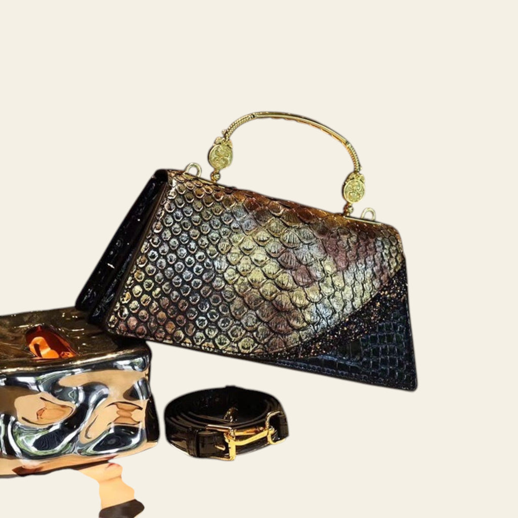 Shiny black handbag with gold accents on a table
