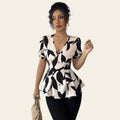Woman wearing a black and white patterned top with a plain background